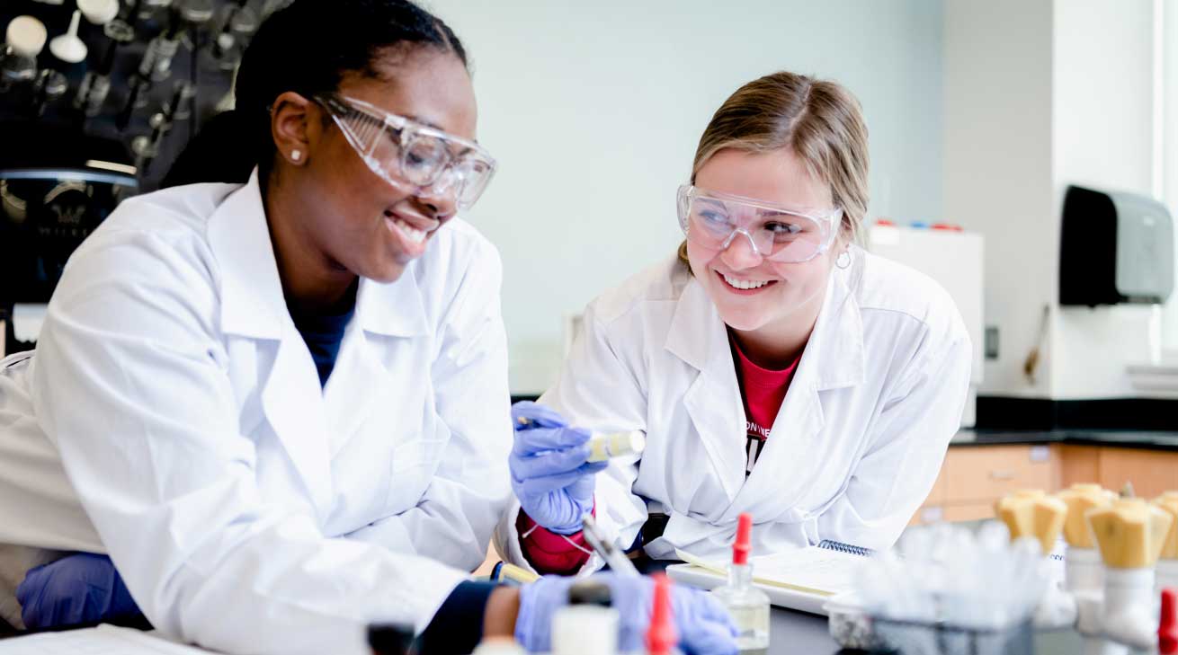 two students in lab with safety gear